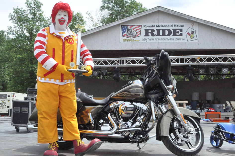 Ronald McDonald poses in front of bike at Ronald McDonald House Ride
